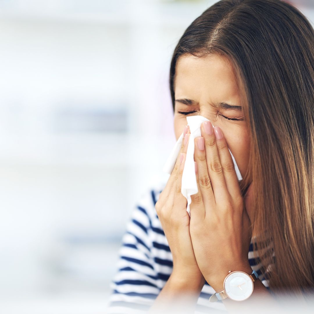 a woman sneezing in a kleenex